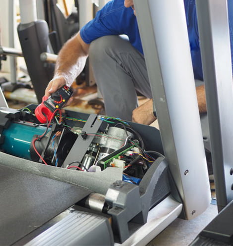 Mężczyzna naprawia bieżnię fitness siłownia Łódź
